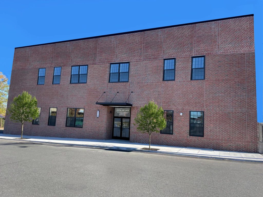 Two-story brick building with multiple windows under clear blue sky.