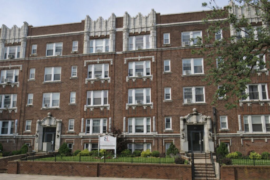 A classic brick apartment building with ornate white trims and balconies.
