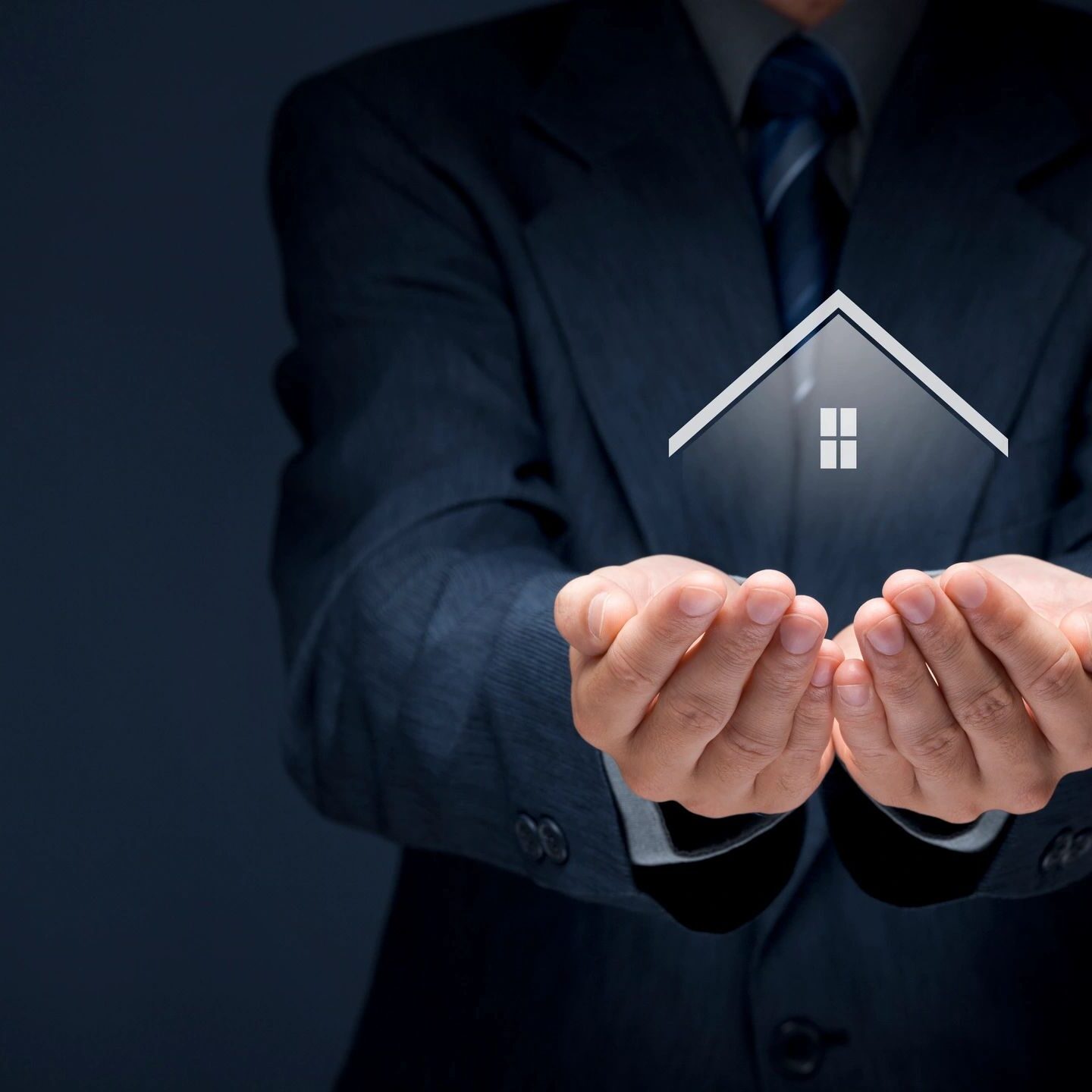 Businessman holding a glowing house icon symbolizing real estate.